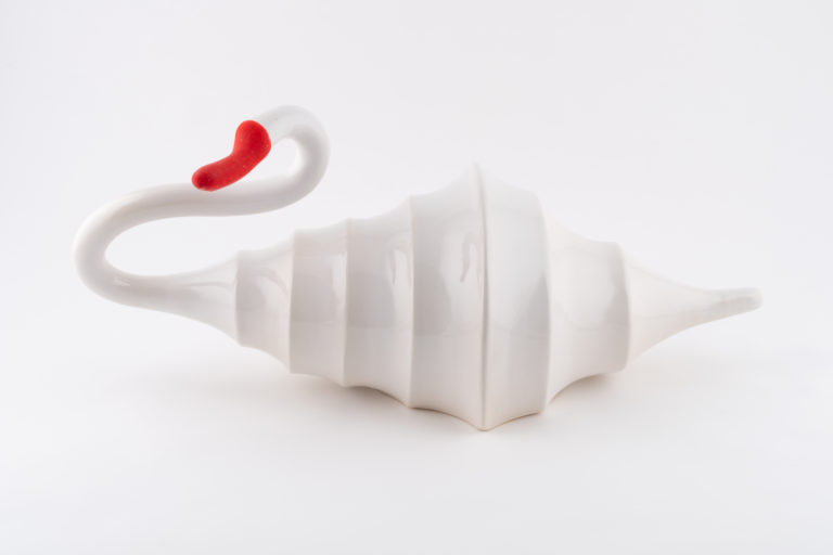 A ceramic white swan shaped like a cone with folded lines it it's back with a bright orange beak