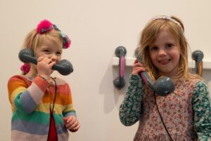 Two young girls interacting with the "Truth Transmitters" in the gallery. Photo by Kate Wolstenholme